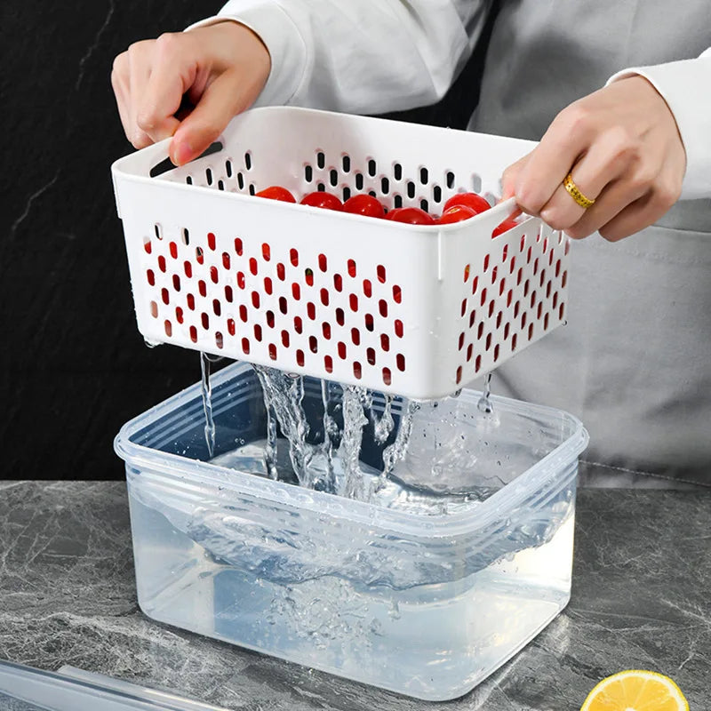 Person washing tomatoes in a white colander over a clear container on a dark surface.