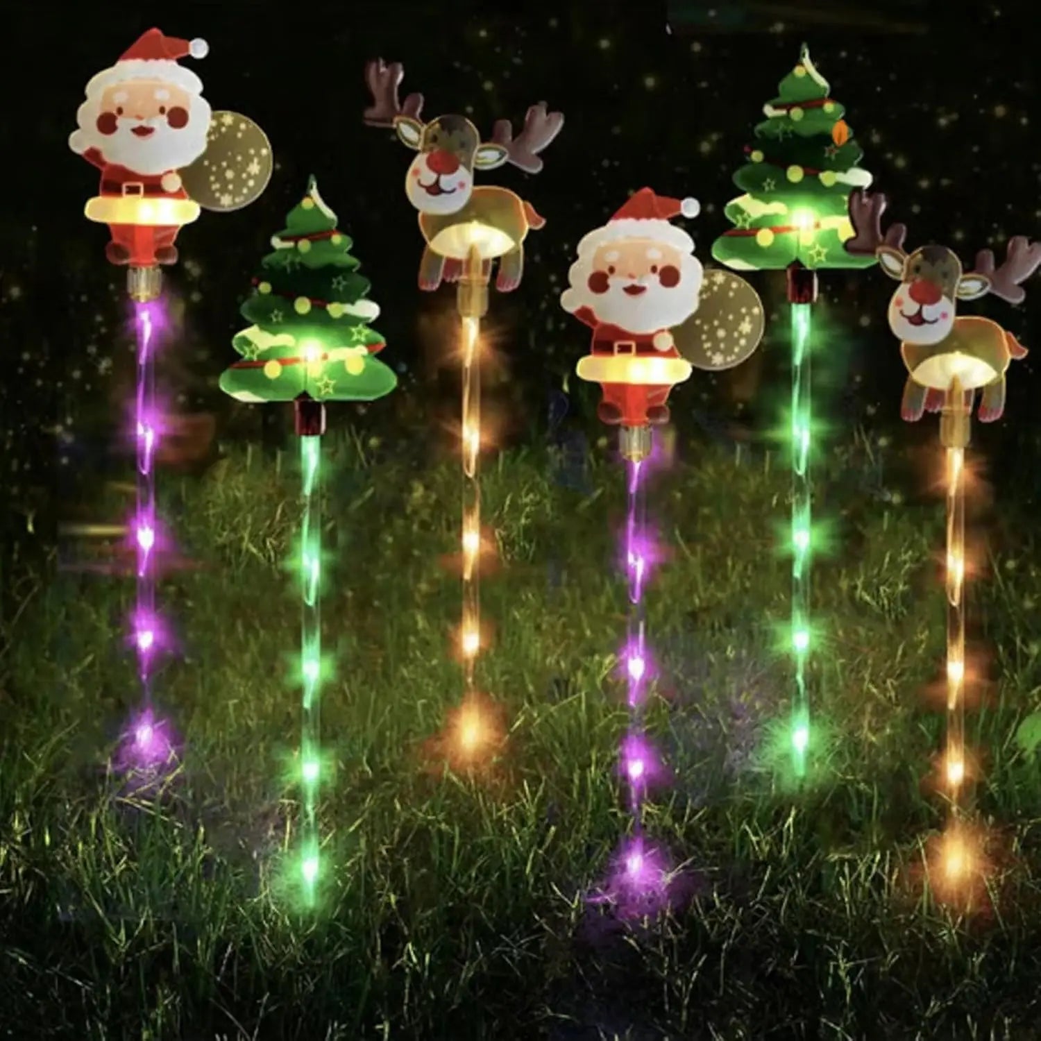 Set of Christmas-themed garden lights including Santa Claus, reindeer, and trees on grass.