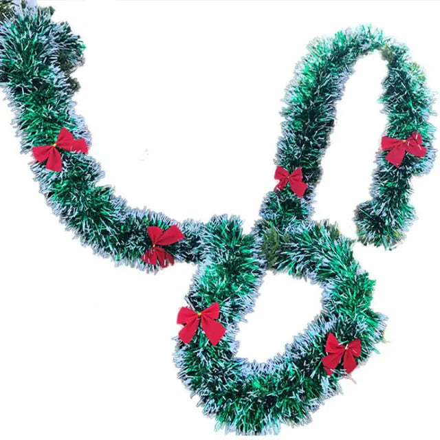 Decorative green tinsel garland with red bows on a white background