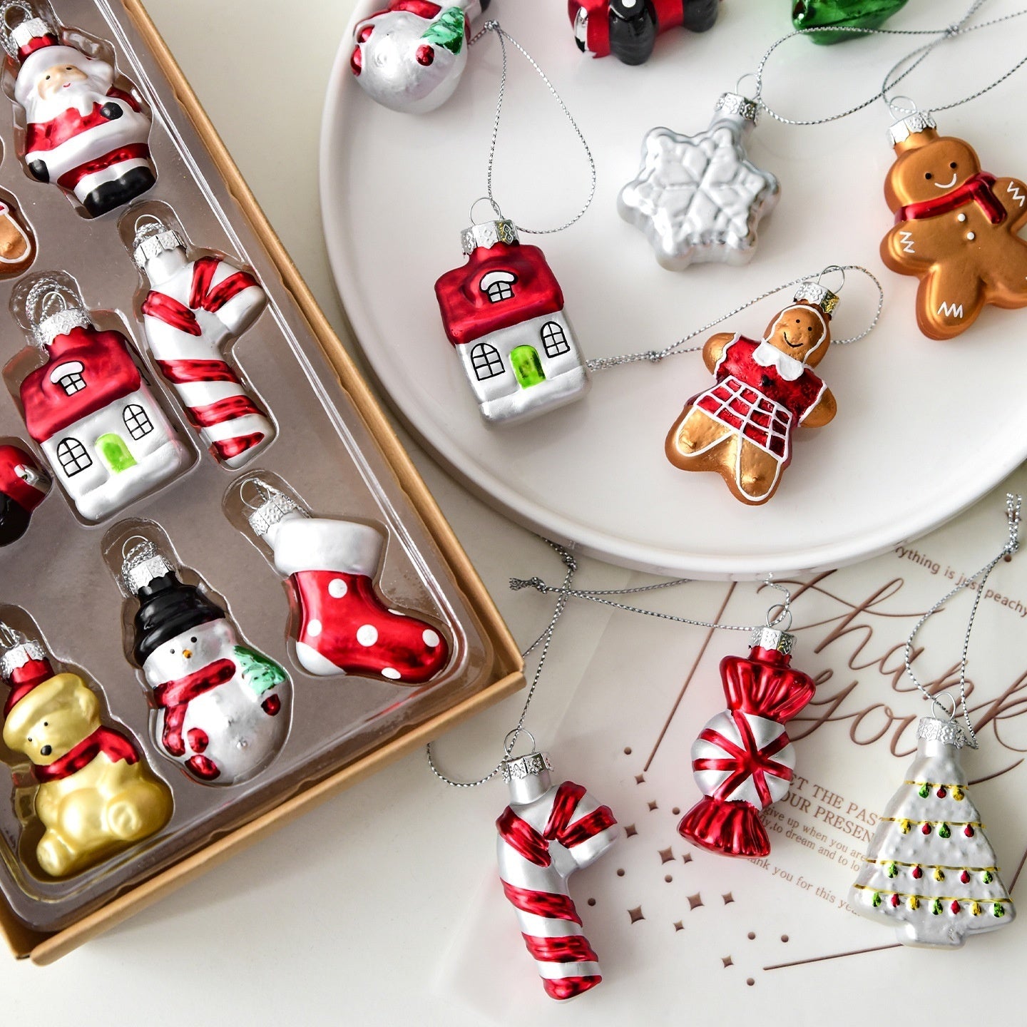Collection of Christmas-themed ornaments including houses, gingerbread men, and candy canes on a white surface.