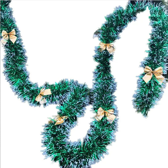 Green tinsel garland with gold bows on a white background
