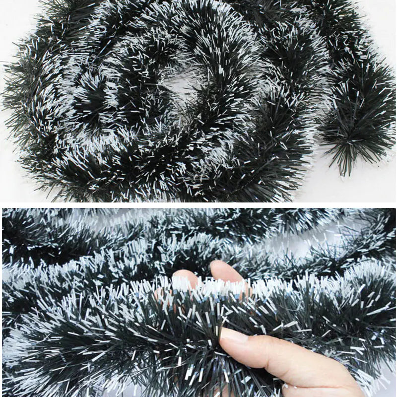 Black tinsel garland with a hand holding it, on a white background