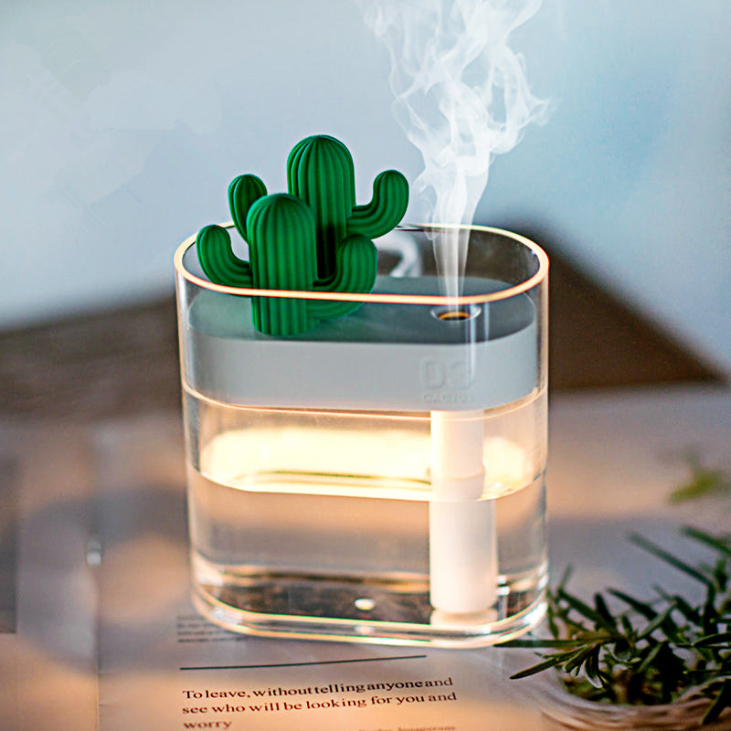 Cactus-shaped diffuser emitting steam in a clear container on a table.